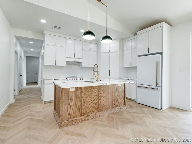 kitchen with visible vents, freestanding refrigerator, recessed lighting, light countertops, and a sink