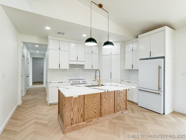kitchen with a sink, light countertops, white fridge, under cabinet range hood, and recessed lighting