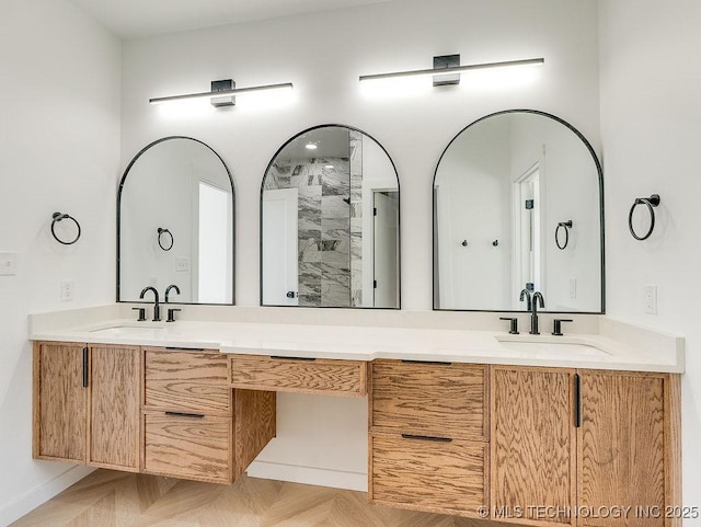 full bathroom with a sink, baseboards, double vanity, and a shower