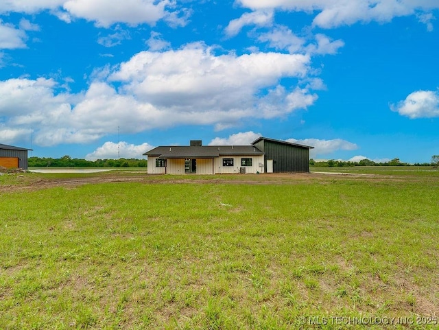 view of front of property with a rural view, driveway, and a front lawn