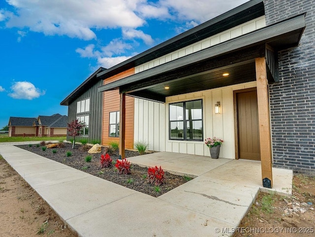 view of exterior entry featuring board and batten siding and brick siding