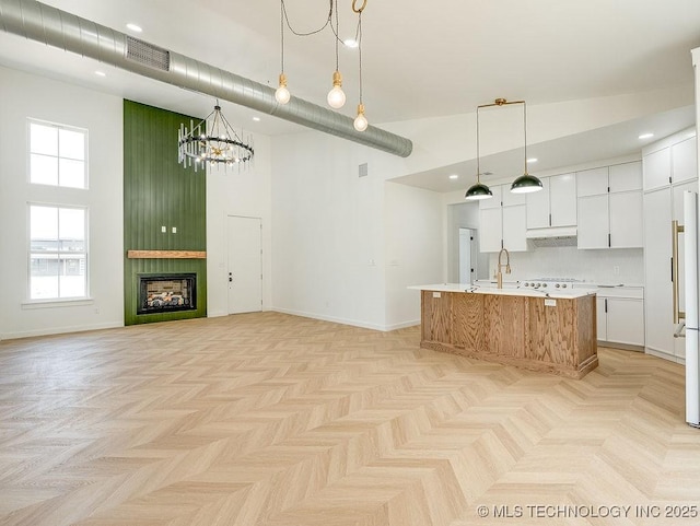 kitchen with a towering ceiling, baseboards, light countertops, white cabinetry, and a notable chandelier