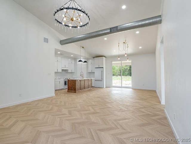unfurnished living room with a notable chandelier, visible vents, baseboards, and high vaulted ceiling