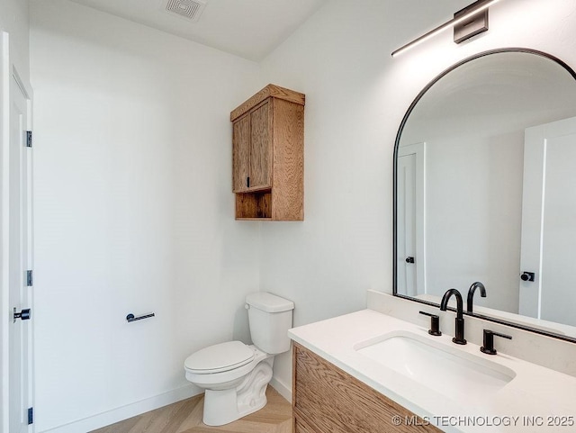 bathroom featuring visible vents, wood finished floors, baseboards, vanity, and toilet