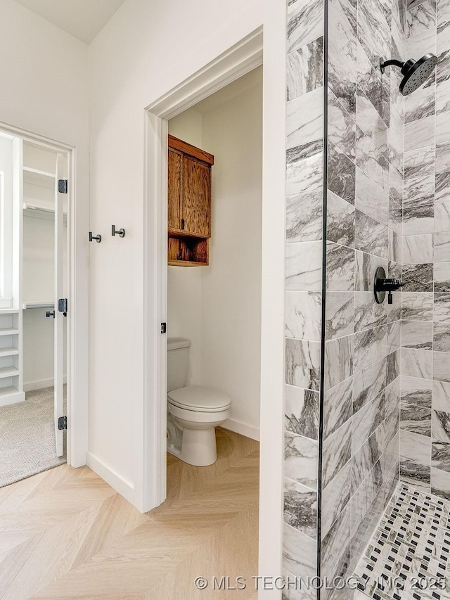 full bathroom with toilet, baseboards, and tiled shower