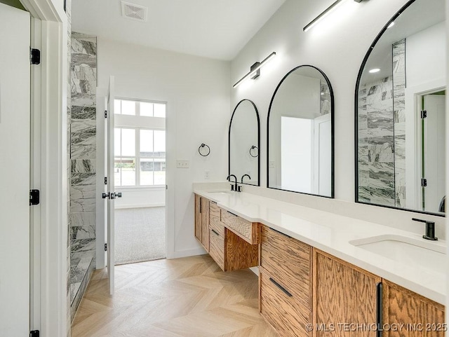 bathroom featuring a sink, a marble finish shower, double vanity, and visible vents