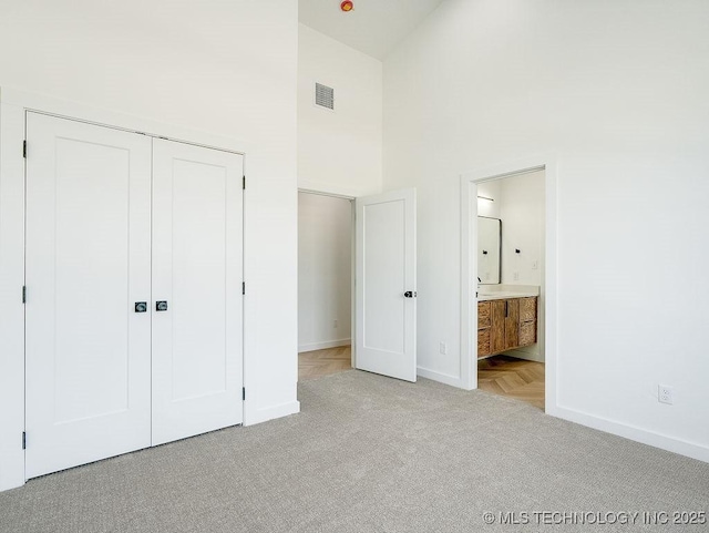 unfurnished bedroom with carpet floors, baseboards, a towering ceiling, and visible vents