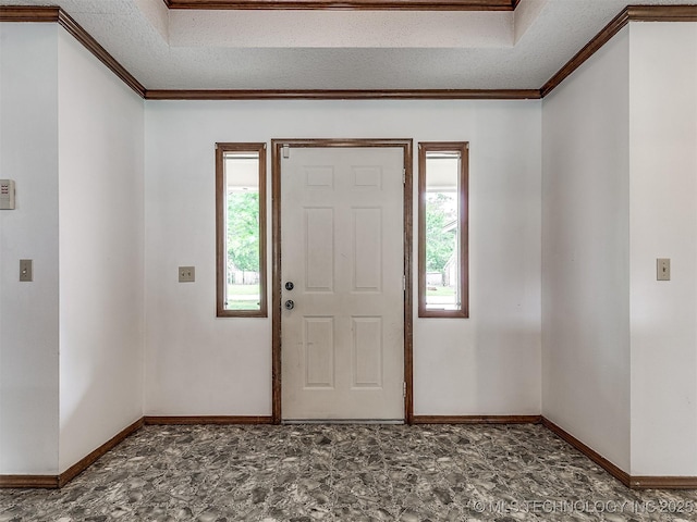 foyer with baseboards, ornamental molding, and a tray ceiling