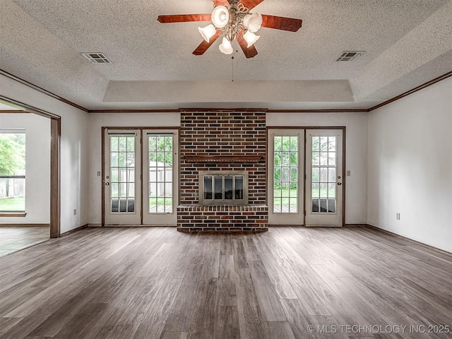 unfurnished living room with visible vents, a textured ceiling, and a tray ceiling