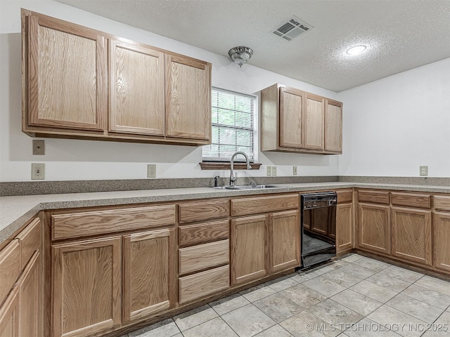kitchen with a sink, a textured ceiling, black dishwasher, light tile patterned floors, and visible vents