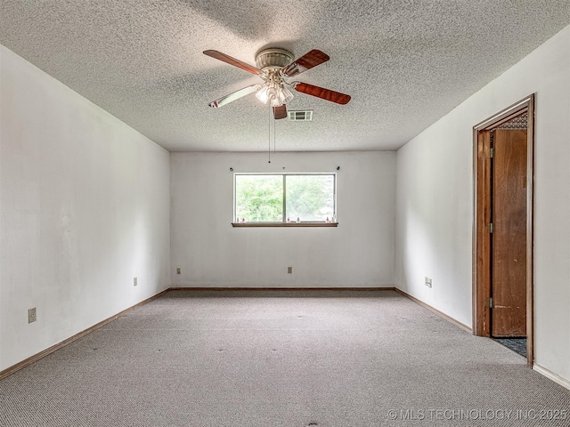 carpeted empty room featuring baseboards, ceiling fan, a textured ceiling, and visible vents