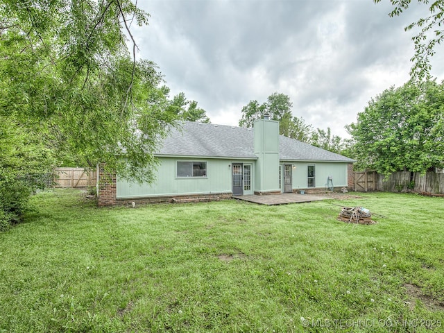 back of property with a chimney, a fenced backyard, and roof with shingles