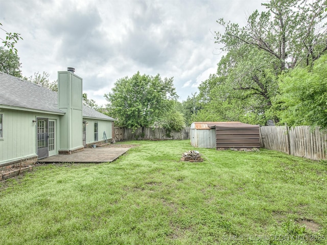 view of yard featuring a fenced backyard, an outbuilding, a deck, and a shed