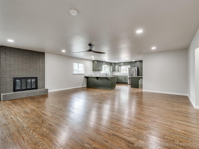 unfurnished living room featuring recessed lighting, ceiling fan, a sink, and wood finished floors