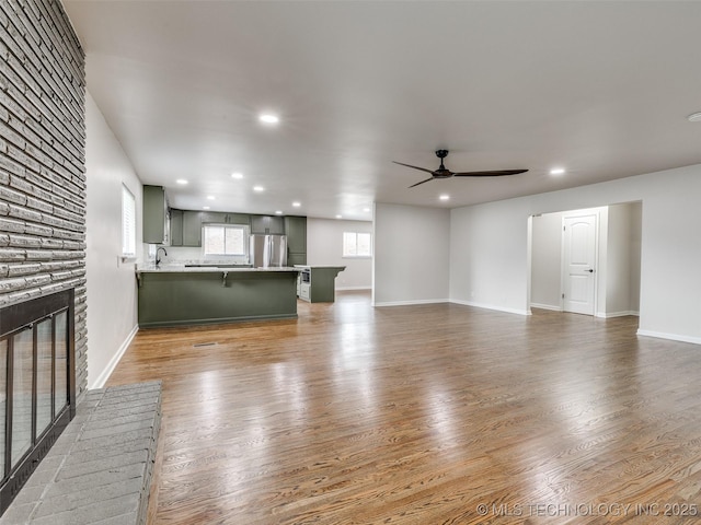 unfurnished living room with a ceiling fan, a sink, wood finished floors, and recessed lighting