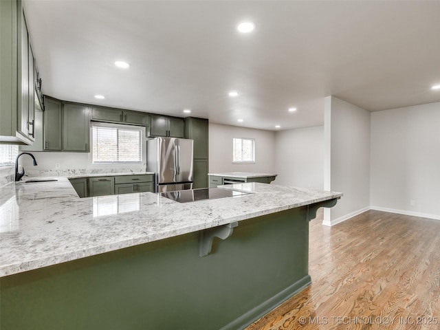 kitchen featuring a sink, freestanding refrigerator, recessed lighting, and black electric stovetop