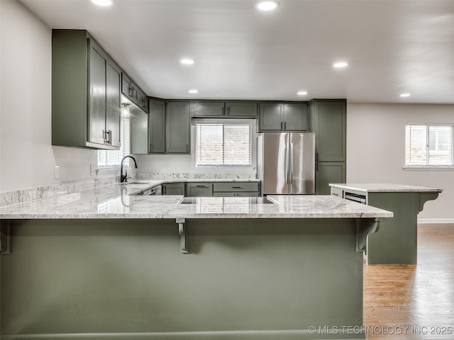 kitchen with freestanding refrigerator, a peninsula, a wealth of natural light, and a sink