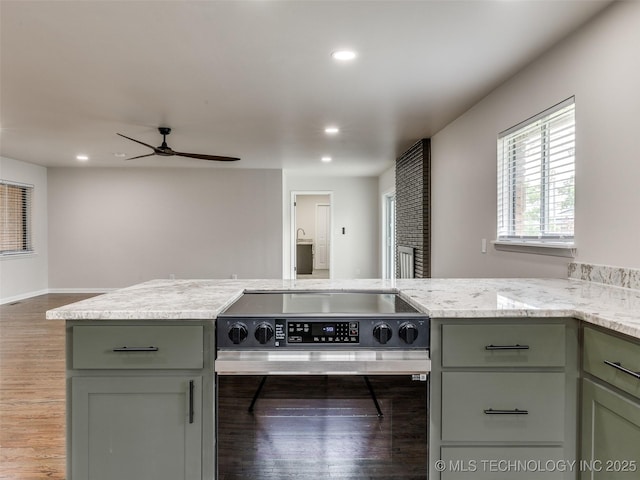 kitchen featuring stainless steel electric range, light stone counters, ceiling fan, recessed lighting, and wood finished floors