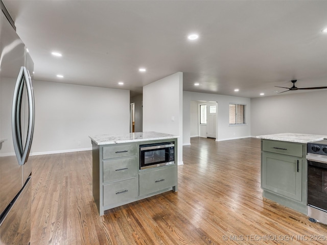 kitchen with ceiling fan, a center island, wood finished floors, open floor plan, and stainless steel appliances