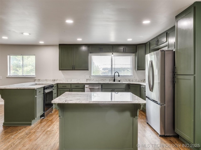 kitchen featuring a sink, green cabinetry, a wealth of natural light, and stainless steel appliances