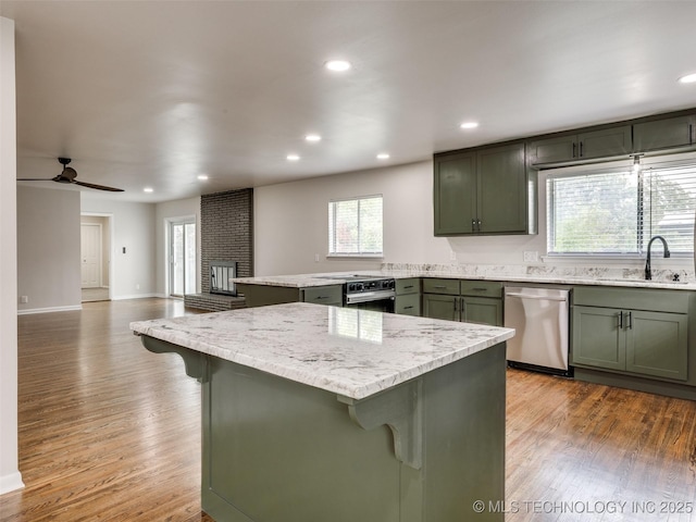 kitchen with a sink, green cabinetry, stainless steel dishwasher, and a kitchen bar