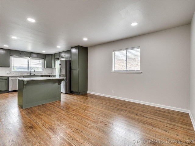 kitchen with appliances with stainless steel finishes, a breakfast bar, light countertops, recessed lighting, and light wood-type flooring