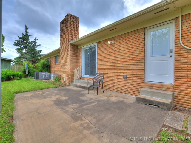 back of property with brick siding, a patio area, a chimney, and entry steps