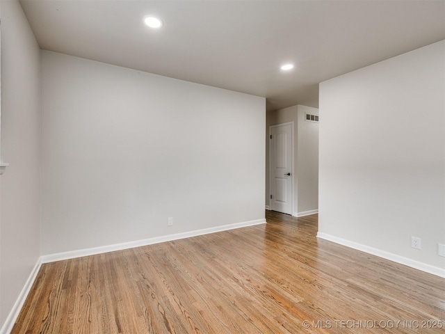 empty room with recessed lighting, baseboards, visible vents, and wood finished floors