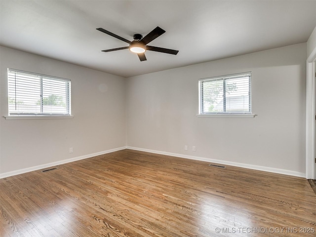 spare room featuring baseboards, ceiling fan, plenty of natural light, and wood finished floors