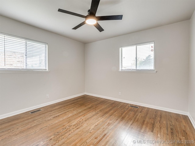 unfurnished room with baseboards, ceiling fan, plenty of natural light, and wood finished floors