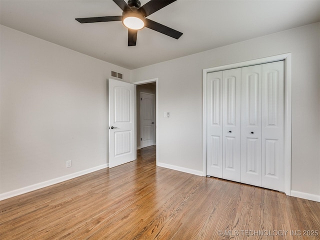 unfurnished bedroom with a ceiling fan, visible vents, baseboards, a closet, and light wood-style flooring