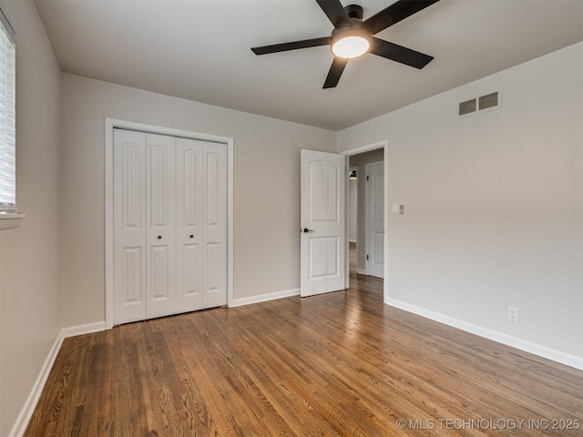 unfurnished bedroom with baseboards, wood finished floors, and visible vents