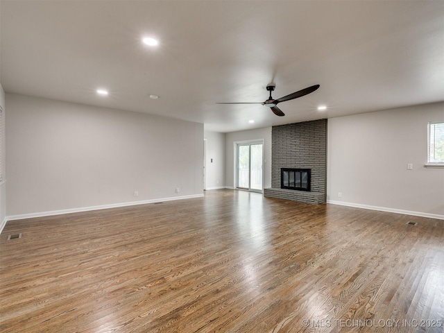 unfurnished living room with plenty of natural light, a ceiling fan, wood finished floors, and visible vents