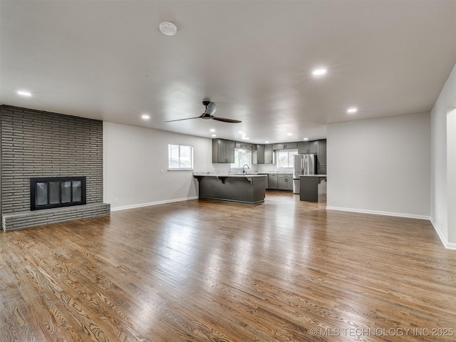 unfurnished living room featuring recessed lighting, baseboards, a sink, and wood finished floors