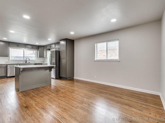 kitchen featuring a breakfast bar, recessed lighting, light wood-type flooring, a sink, and stainless steel appliances
