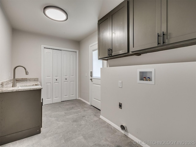 washroom featuring washer hookup, electric dryer hookup, cabinet space, a sink, and baseboards