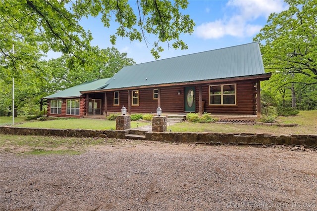 view of front of home with covered porch, log exterior, metal roof, and a front yard