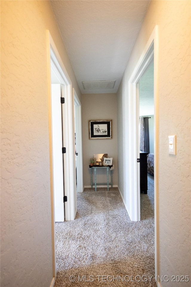 corridor featuring a textured wall and carpet