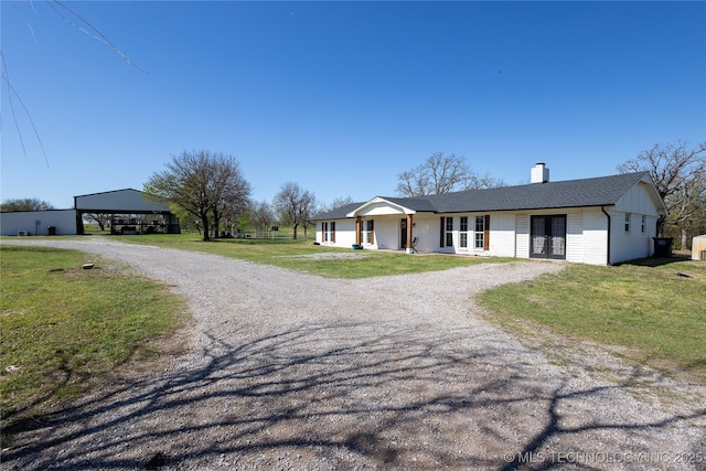 ranch-style home featuring driveway, french doors, a front lawn, and a chimney