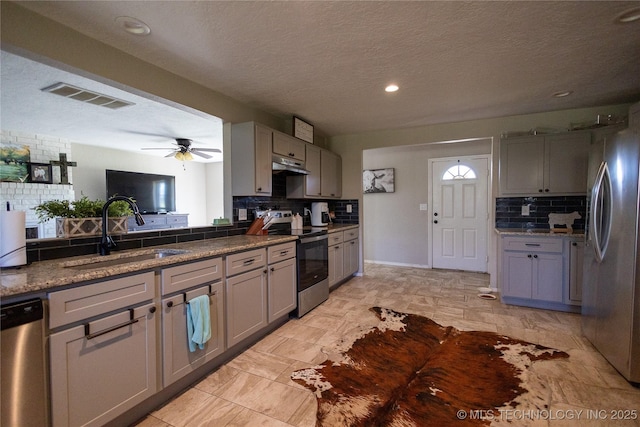 kitchen featuring visible vents, decorative backsplash, under cabinet range hood, a sink, and stainless steel appliances