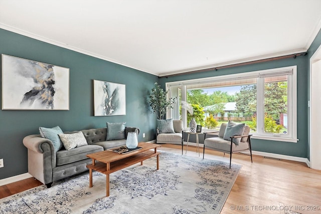 living room featuring baseboards, ornamental molding, wood finished floors, and visible vents