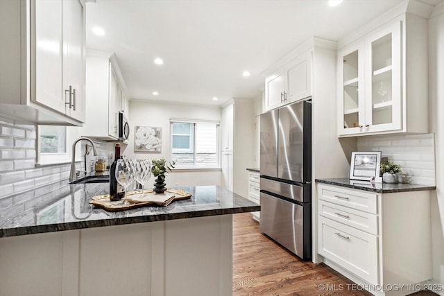kitchen featuring decorative backsplash, a sink, glass insert cabinets, stainless steel appliances, and white cabinetry