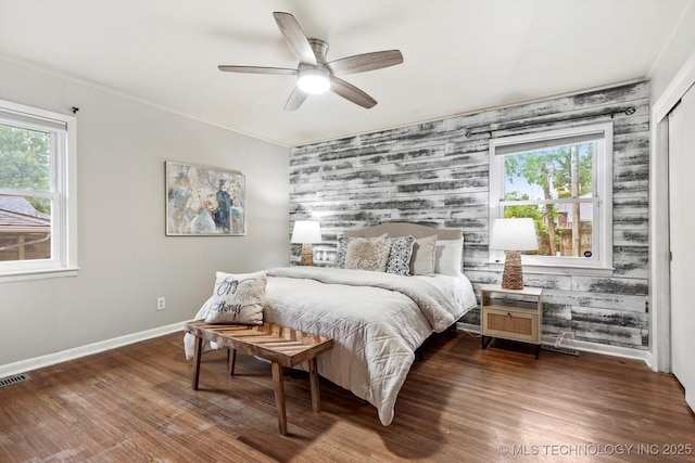 bedroom featuring baseboards, an accent wall, and multiple windows