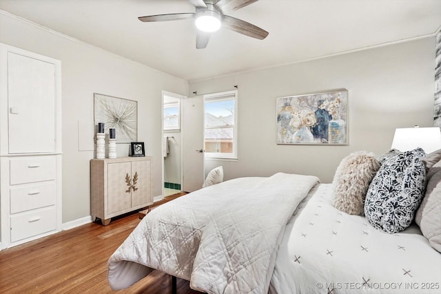 bedroom with baseboards, a ceiling fan, crown molding, and wood finished floors