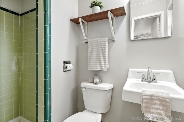 full bathroom featuring a sink, a tile shower, and toilet