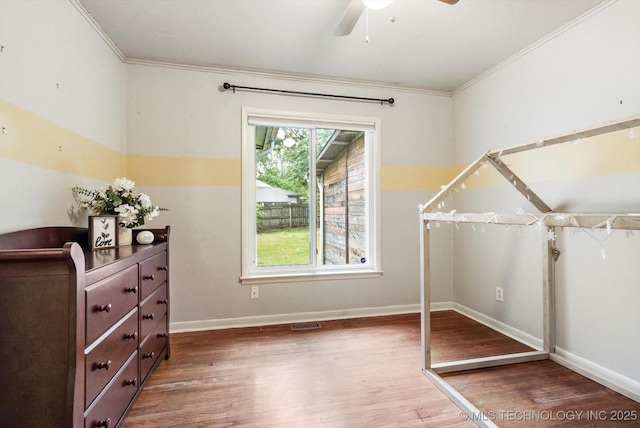 unfurnished bedroom with baseboards, ornamental molding, wood finished floors, and visible vents