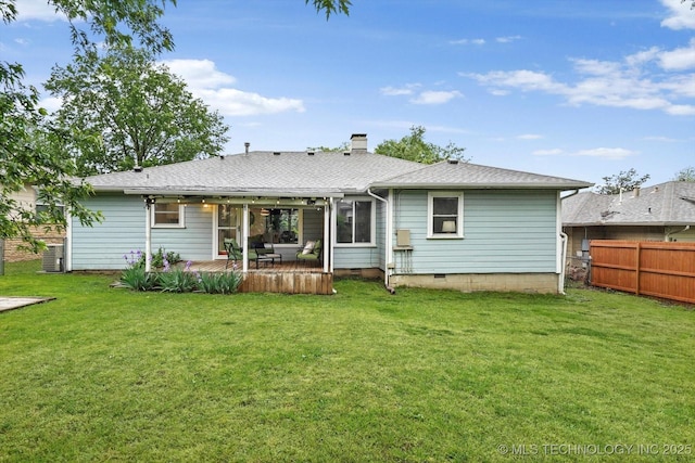 rear view of property featuring roof with shingles, fence, a yard, and a chimney