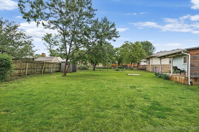 view of yard with a fenced backyard, a shed, and an outbuilding