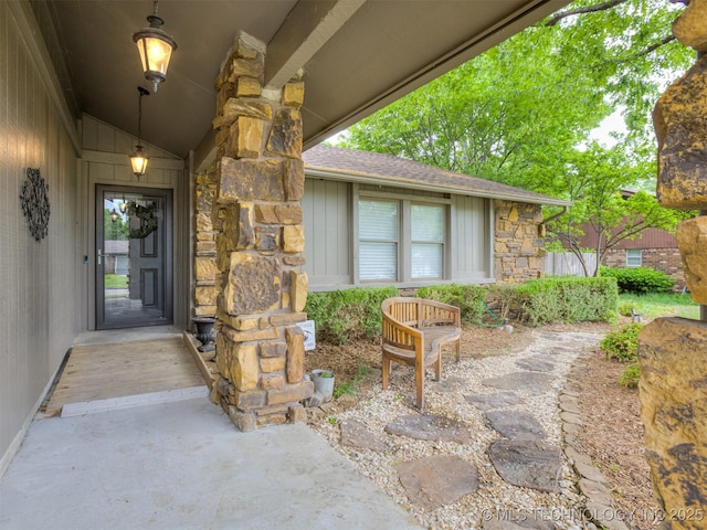 view of exterior entry with board and batten siding, a shingled roof, and stone siding