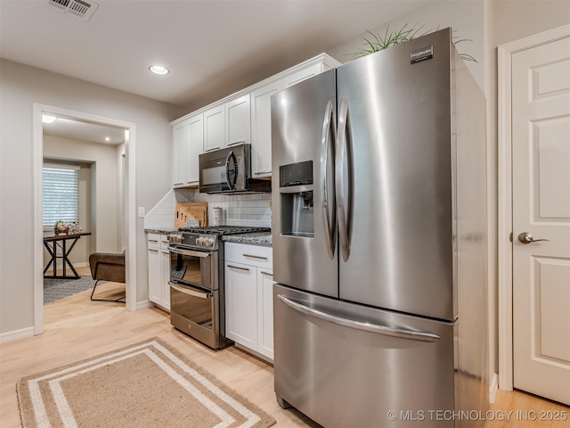 kitchen with visible vents, decorative backsplash, white cabinetry, and stainless steel appliances
